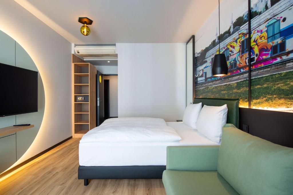 ein Schlafzimmer mit einem Bett, einem Sofa und einem TV in der Unterkunft Vienna House Easy by Wyndham Berlin Potsdamer Platz in Berlin