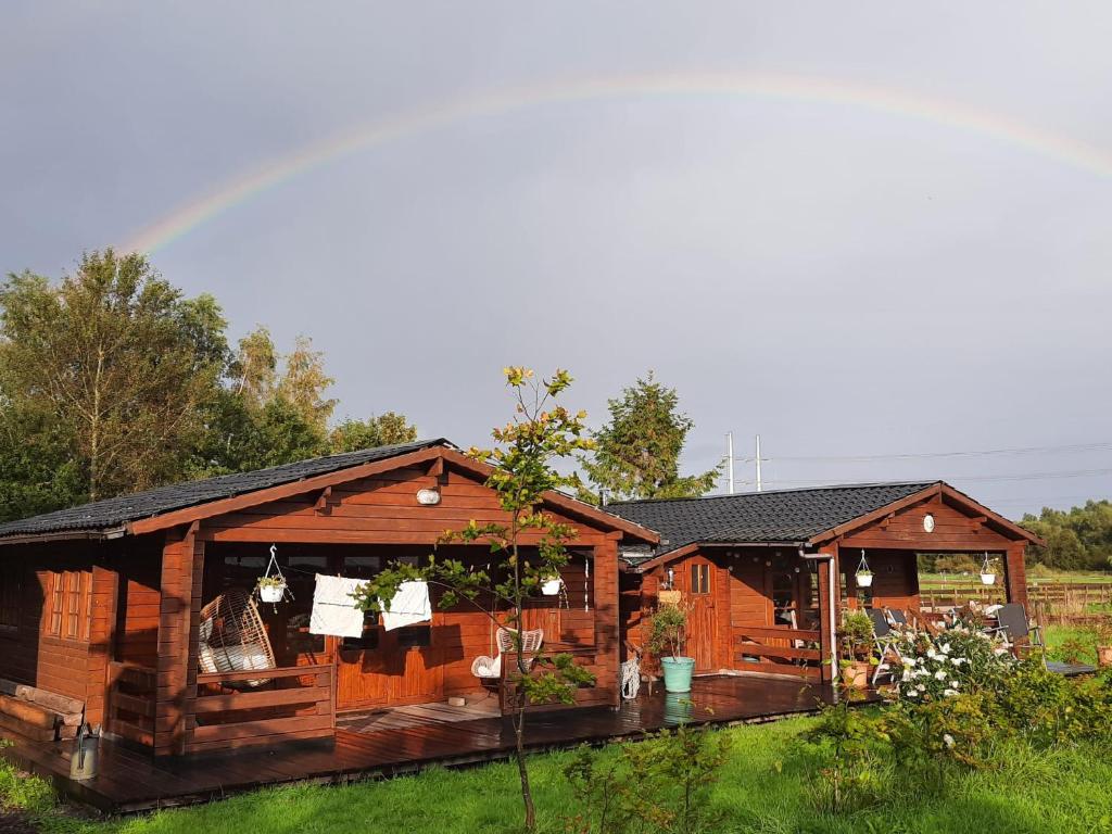 een paar houten gebouwen met een regenboog op de achtergrond bij Ruime romantische blokhut in Zwaanshoek