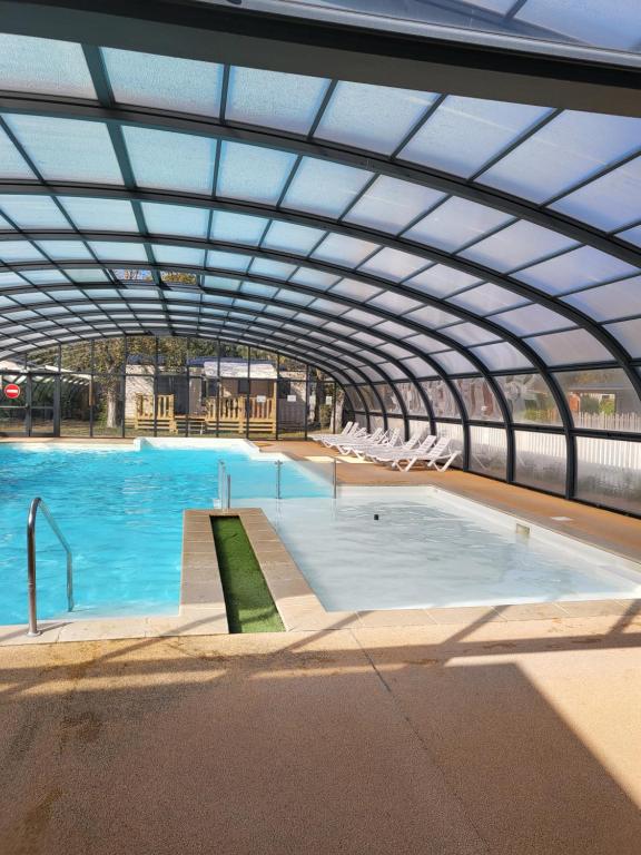 a large swimming pool with a large roof at Camping Riva Bella - Mobil home Les4L in Ouistreham