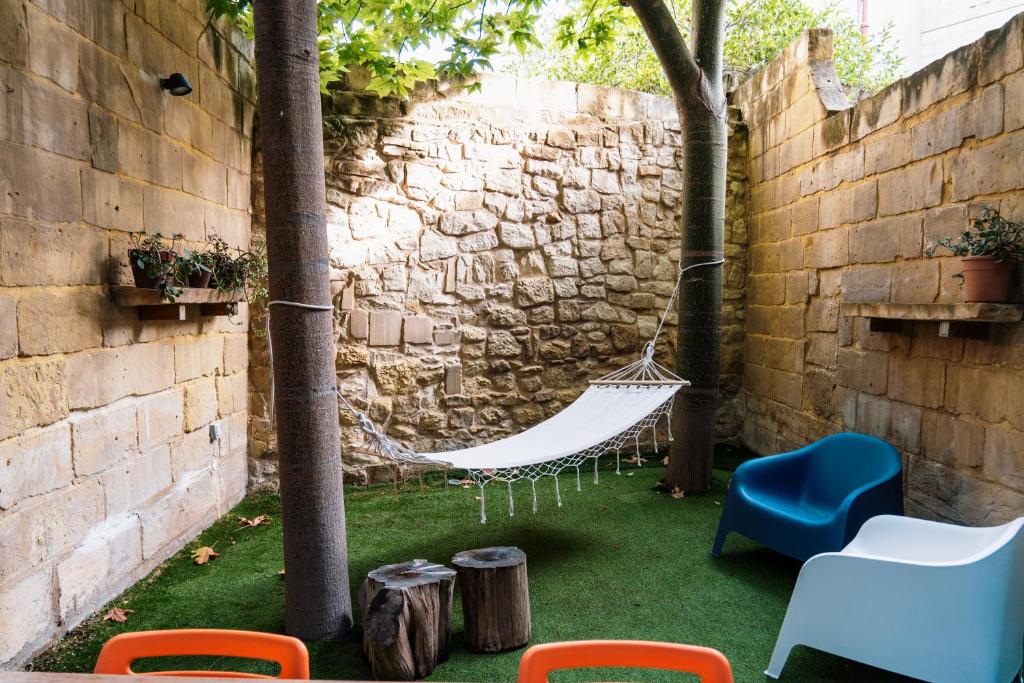 a hammock in a backyard with a stone wall at Luxurious eclectic home in a traditional village in Tarxien
