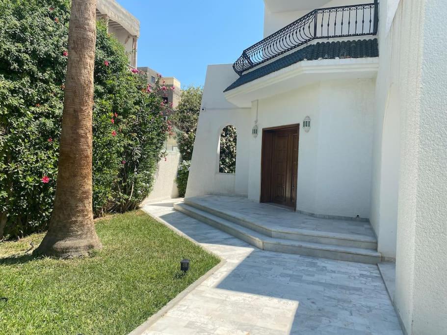 una casa blanca con una puerta y una palmera en Villa de maitre magnifique, spacieuse avec jardin, en La Marsa