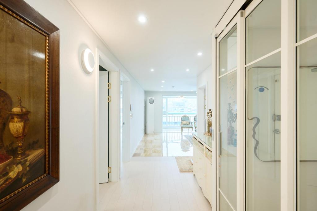 a hallway with white walls and glass doors at Garosugil Homestay - Female Only in Seoul