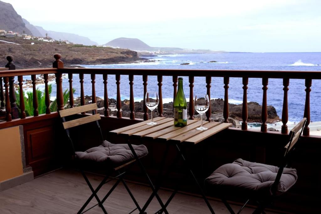 a table with two glasses of wine on a balcony at Apartamento primera línea mar Garachico in Garachico