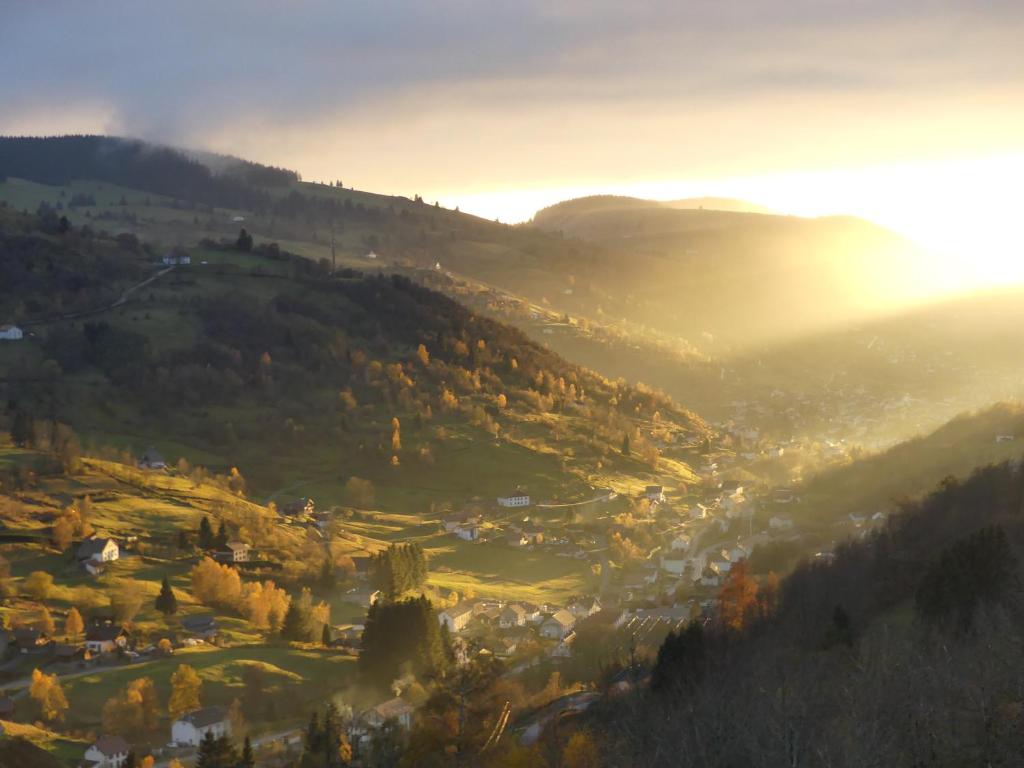 a view of a valley in the mountains with the sun setting at LE MASSIF - Appartement avec vue imprenable in La Bresse
