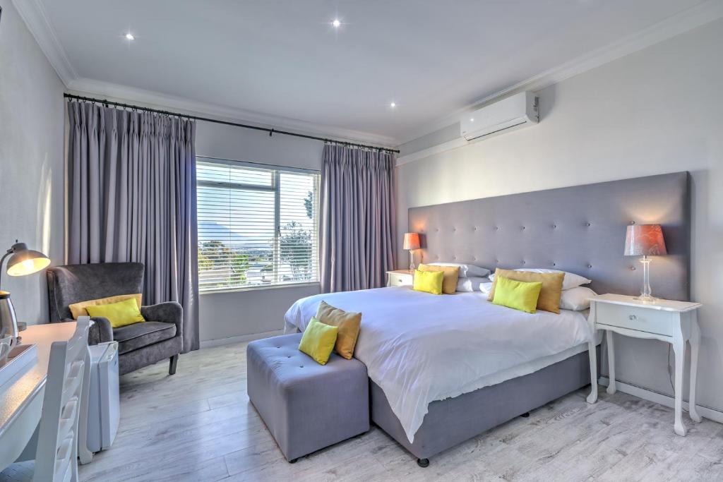 ein Schlafzimmer mit einem großen Bett und einem Stuhl in der Unterkunft Thyme Wellness Spa and Guesthouse in Kapstadt