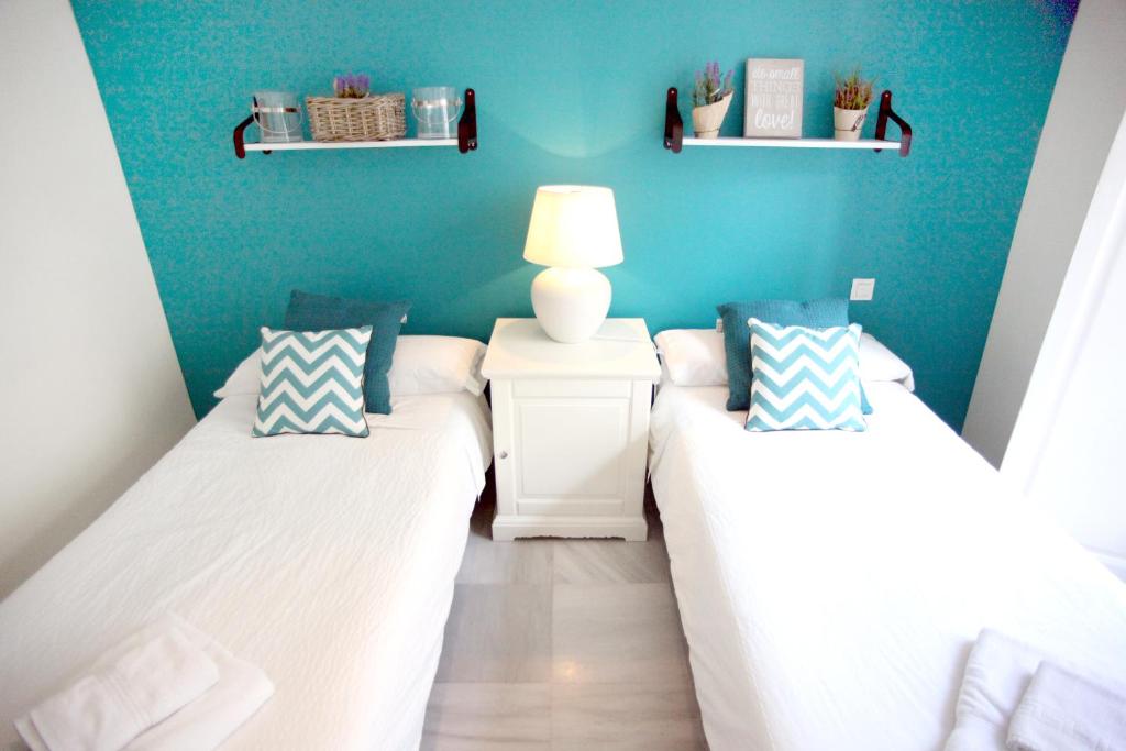 a bedroom with two beds and a blue wall at Sleepin Sevilla Catedral in Seville