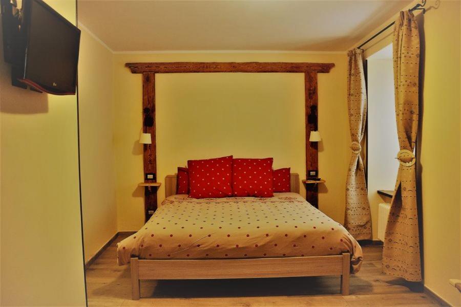 a bedroom with a bed with red pillows and a television at La Boule de Neige in Pré-Saint-Didier