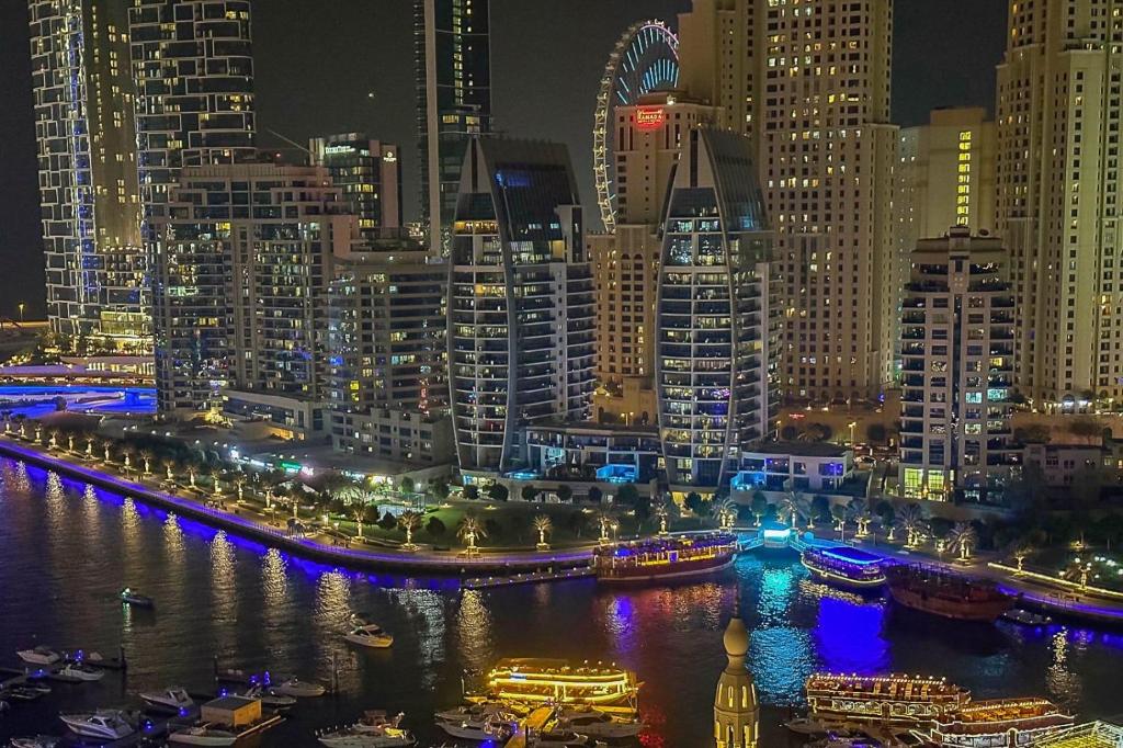 um horizonte da cidade à noite com barcos na água em Marina Yacht Club Views - 3BR Modern Furnished no Dubai