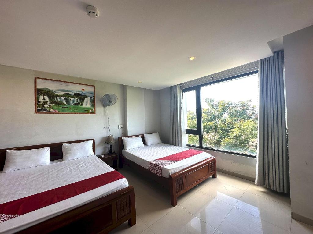 a bedroom with two beds and a large window at OYO 1201 Huy Hoang Hotel in Da Nang