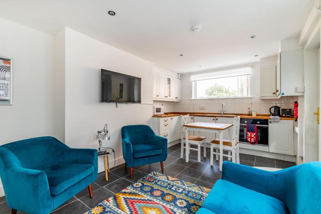 a living room with two blue chairs and a kitchen at Park View in Great Yarmouth