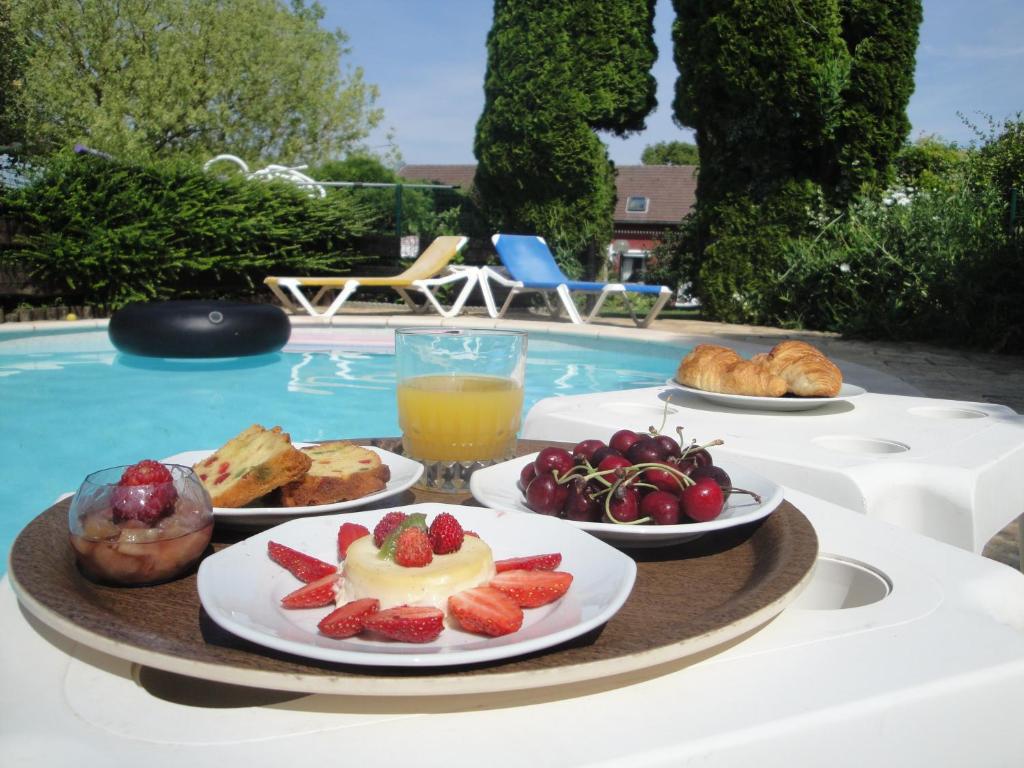 una bandeja de comida con fruta en una mesa junto a la piscina en Ferme Auberge Du Vieux Puits, en Bony