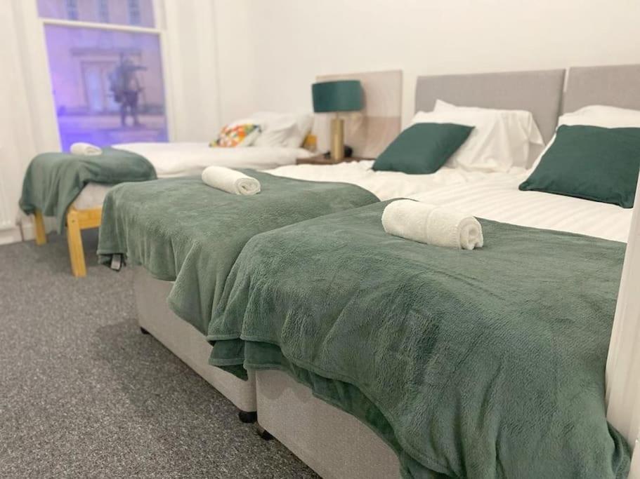 two beds in a room with green and white blankets at Central Bridgewater Flat in Bridgwater