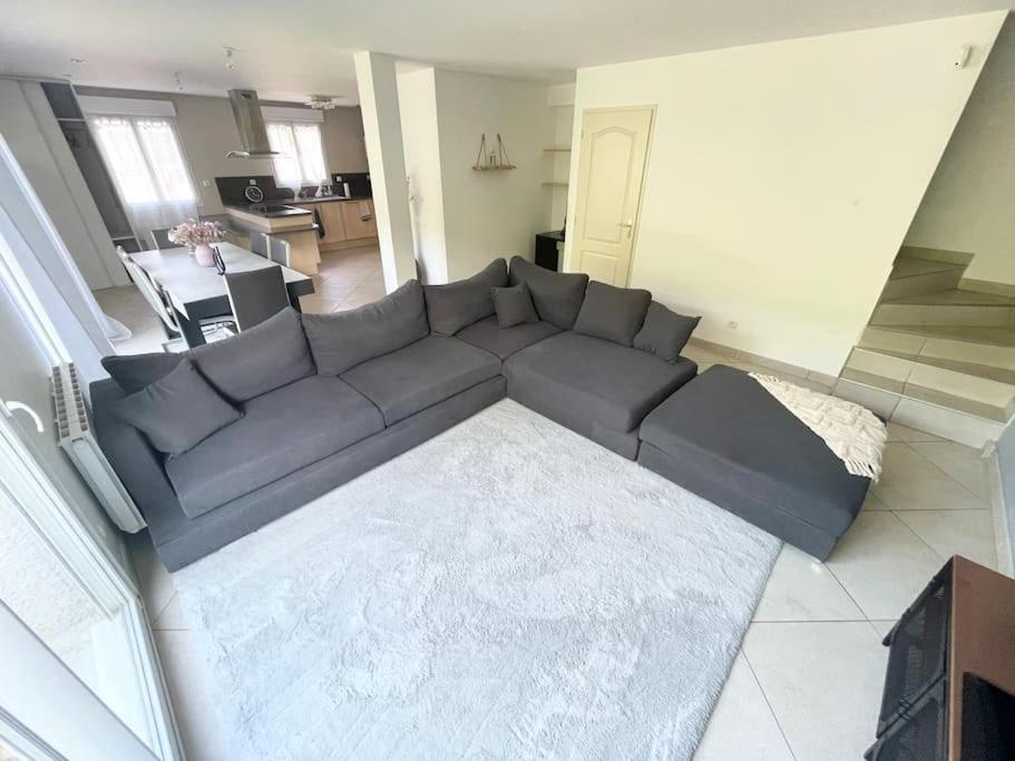 a living room with a black couch in a living room at Agréable et grande maison avec parking + jardin in Villeurbanne