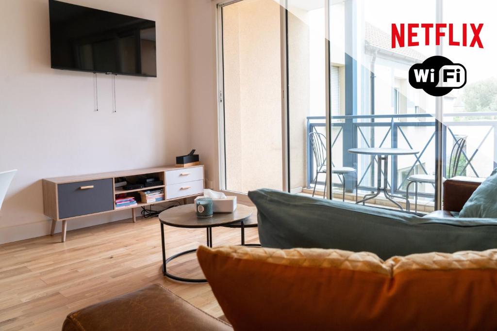 a living room with a couch and a tv at Escapade à la mer in Dunkerque