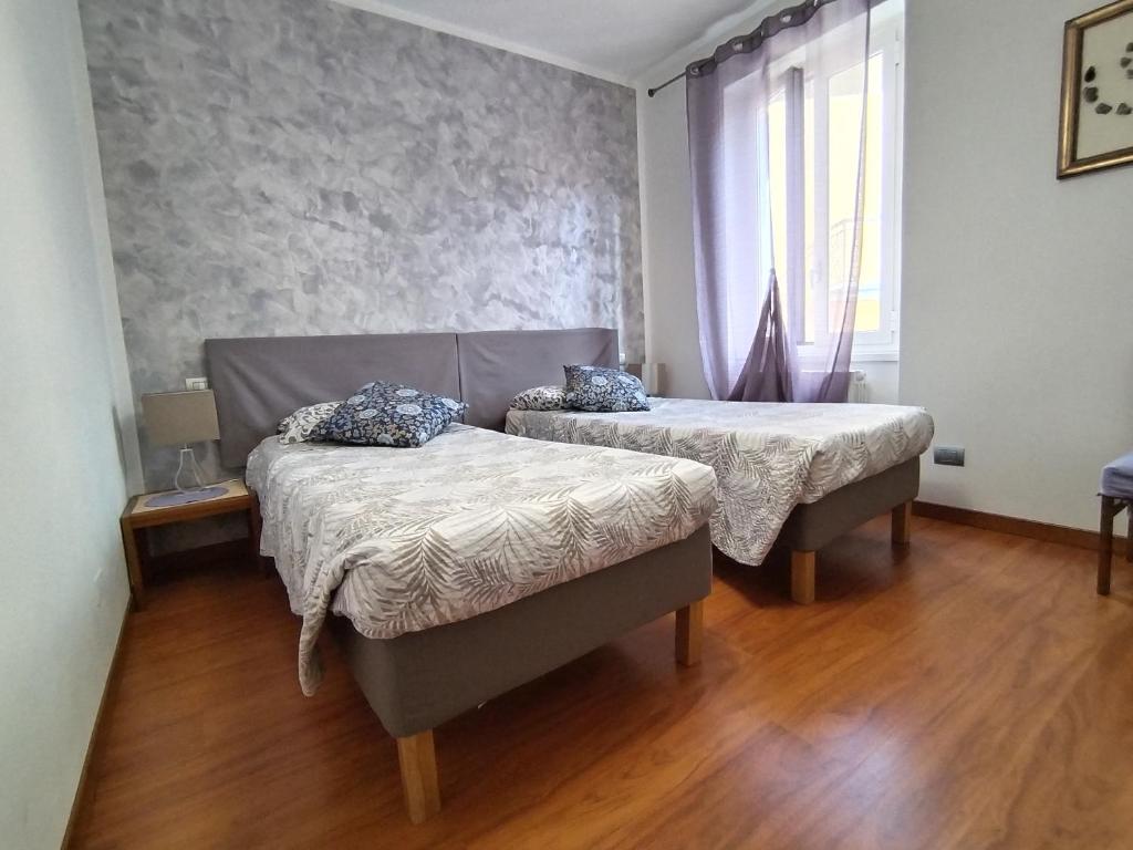 2 łóżka w pokoju z drewnianą podłogą i oknem w obiekcie B & B Ametista Bergamo w mieście Ponteranica