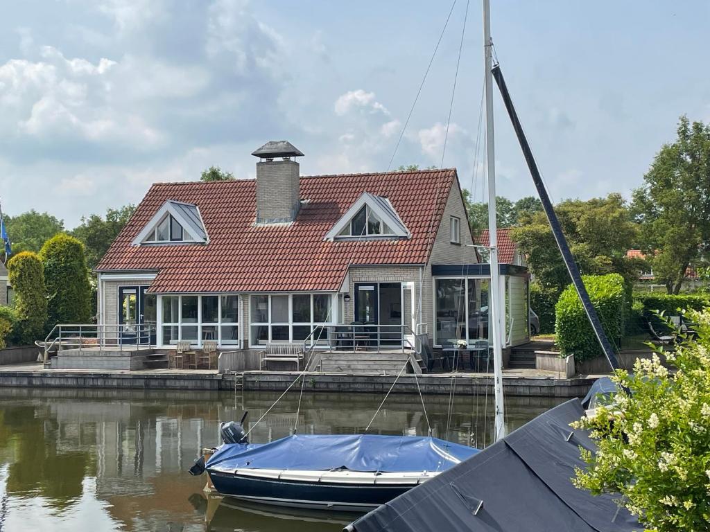a boat docked in front of a house on the water at Watervilla de Rietzanger by Droomvilla in Langweer