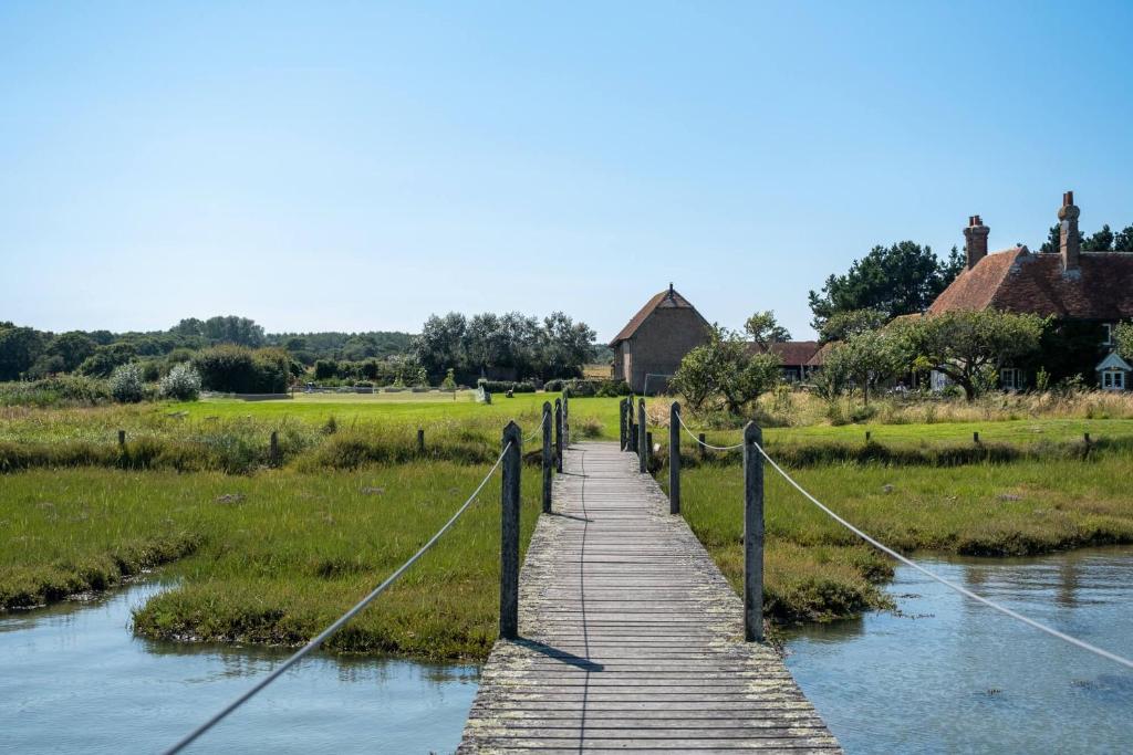 a wooden bridge over a river in a field at Gins Barn in Southampton