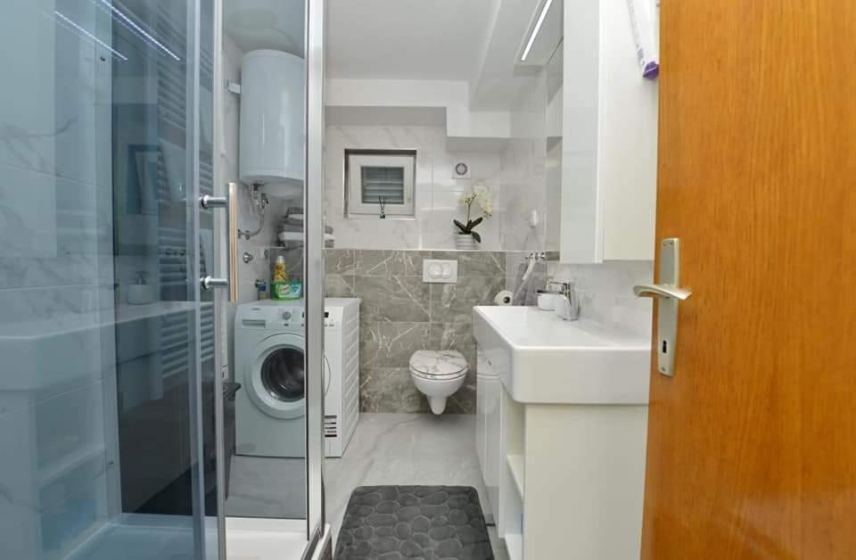 a bathroom with a sink and a washing machine at D&J Apartment Zadar in Zadar