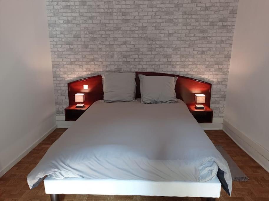 a bedroom with a large white bed with two lamps at Appartement le bar du JURA in Saint-Claude