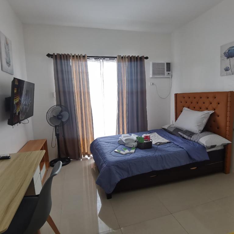 Un dormitorio con una cama azul y una ventana en Affordable Condo w/ Shower Heater and Wi-Fi, en Minglanilla