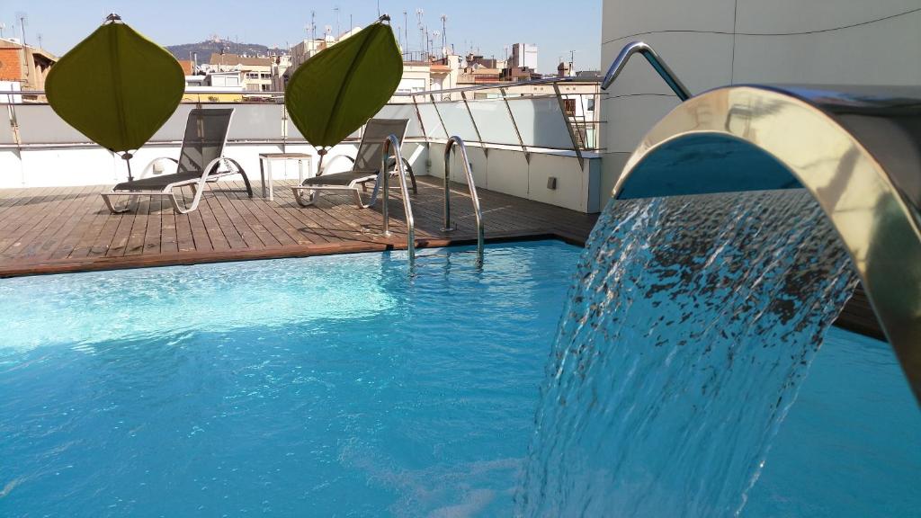 a swimming pool with a water fountain in the middle at Ako Suites Hotel in Barcelona