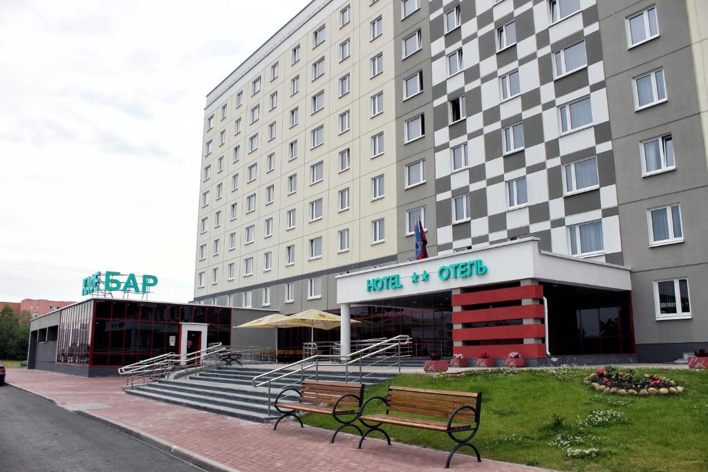 a hotel with two benches in front of a building at IT Time Hotel in Minsk