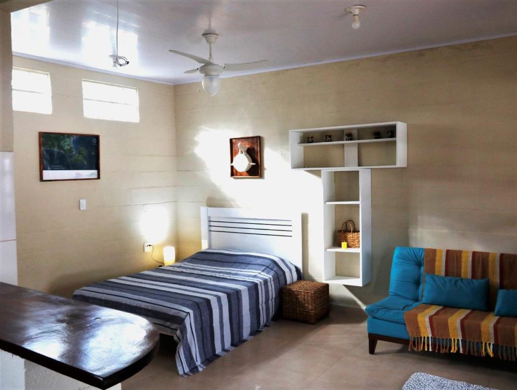 um quarto com uma cama e uma cadeira azul em Rancho do Capitão Boiçucanga em São Sebastião