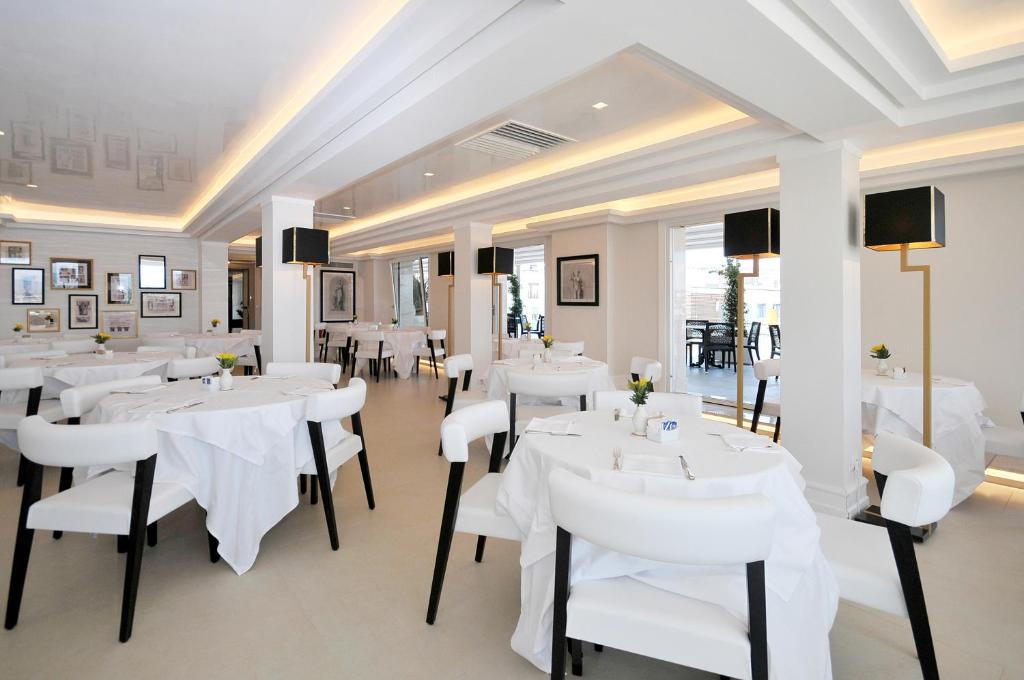 restauracja z białymi stołami i białymi krzesłami w obiekcie Grand Hotel Oriente w mieście Neapol