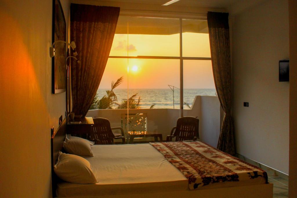 a bedroom with a bed and a view of the ocean at Hotel Coconut Bay in Kalutara