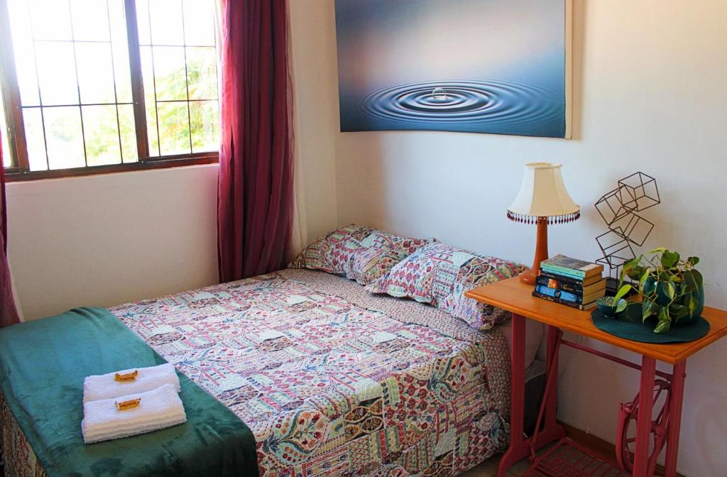 1 dormitorio con 1 cama y 1 mesa con lámpara en Cosy Boho Cottage - All to Yourself!, en Durban