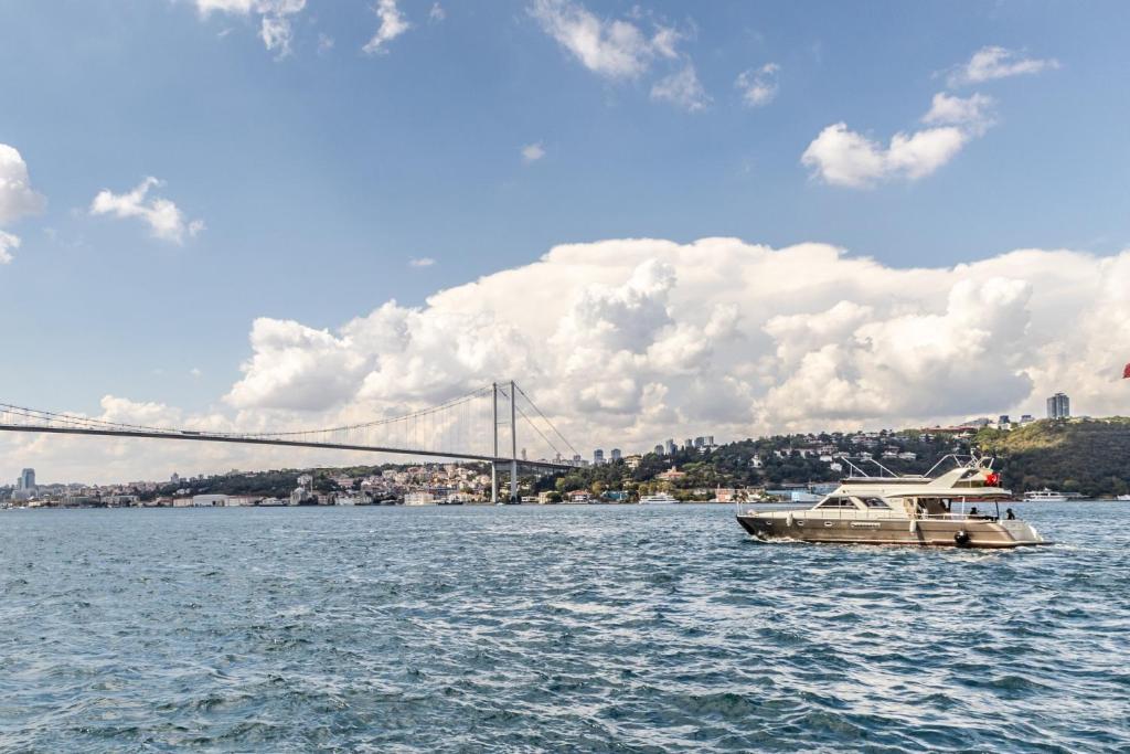 Sea View Studio Flat Near Beylerbeyi Palace في إسطنبول: قارب في الماء مع جسر في الخلفية