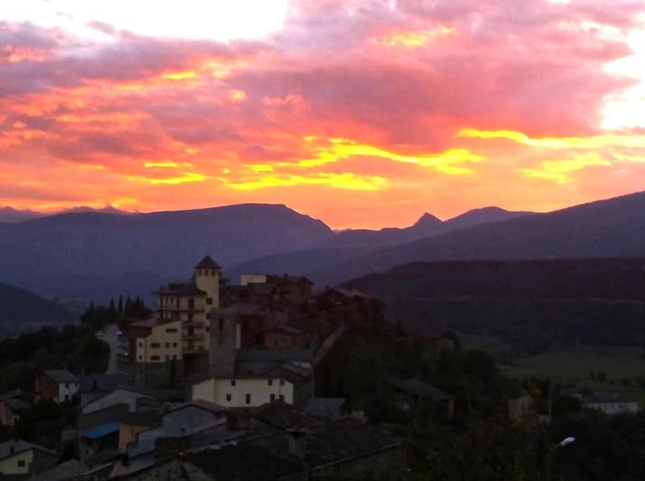 um pôr-do-sol sobre uma cidade numa colina com montanhas em Apartament Gran Pirineu em Montferrer