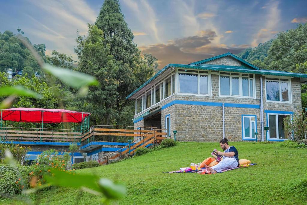 Un gruppo di persone sedute sull'erba di fronte a una casa di SaffronStays Kasauli Estate a Kasauli