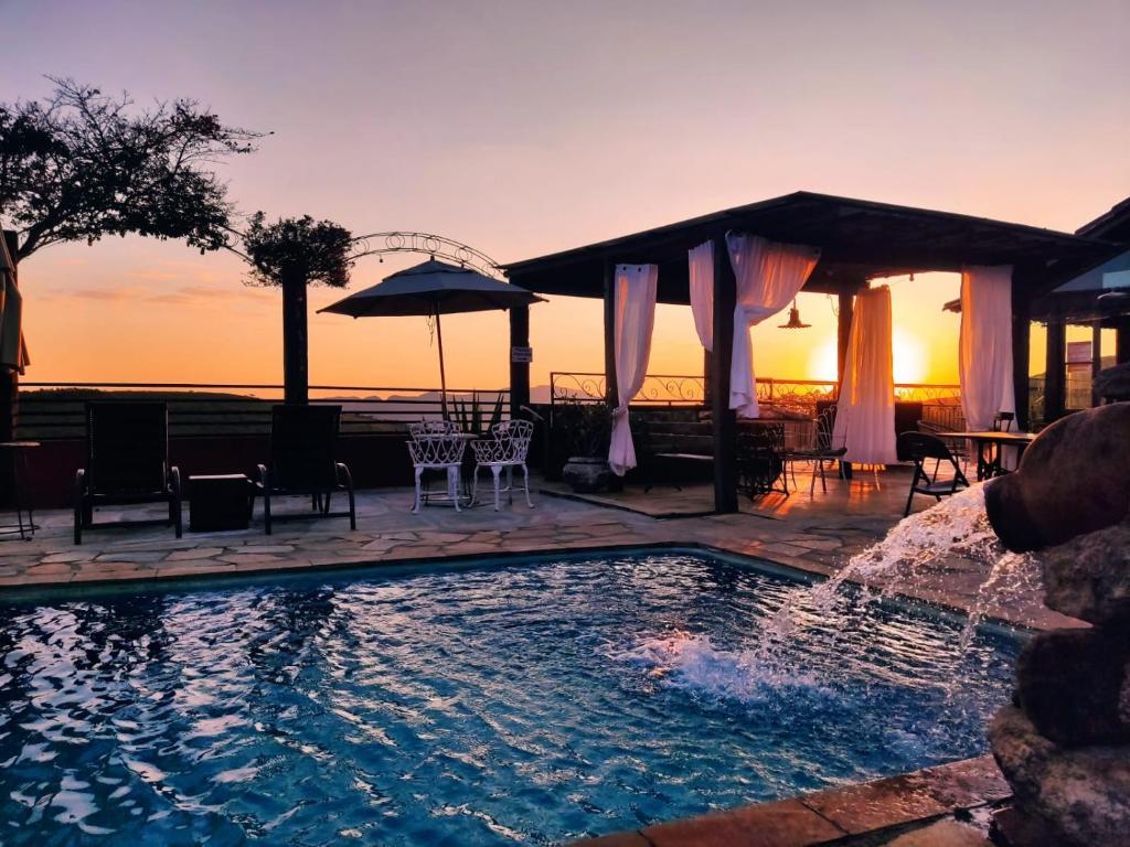 a swimming pool with a sunset in the background at Pousada Palavras Novas in Lavras Novas