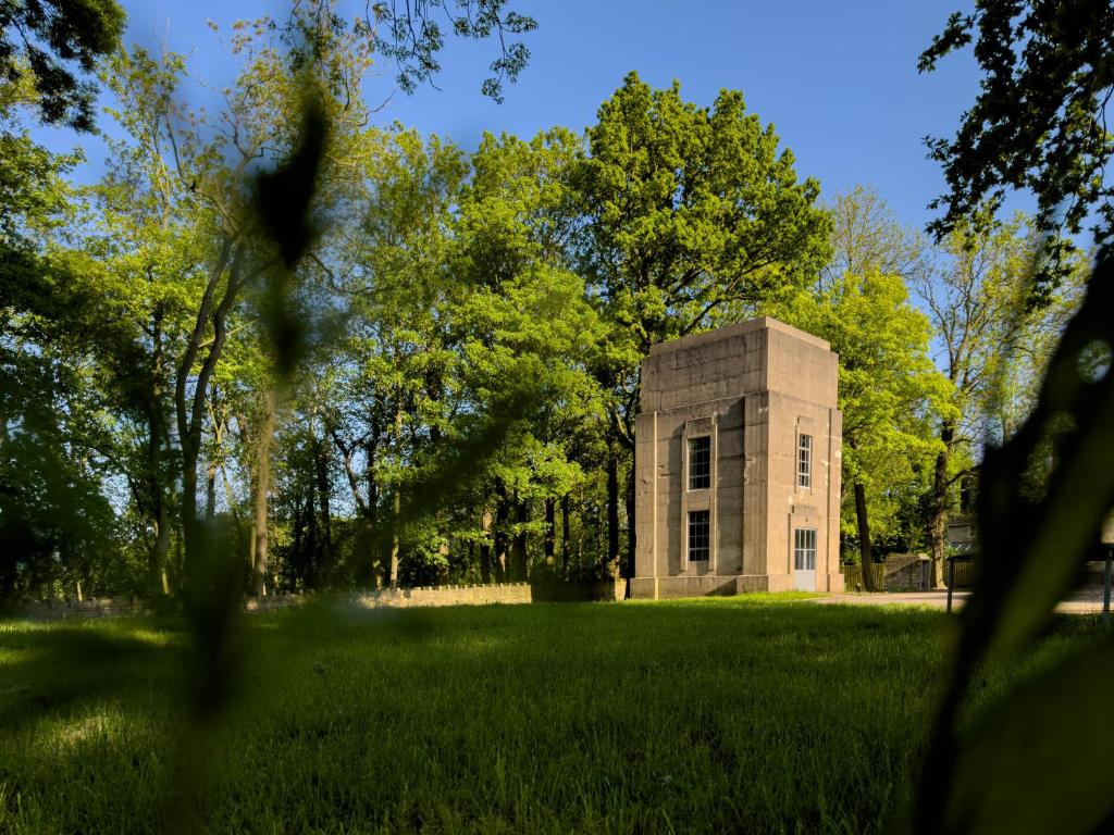 a small stone building in a field with trees at The Tower in Chesterfield