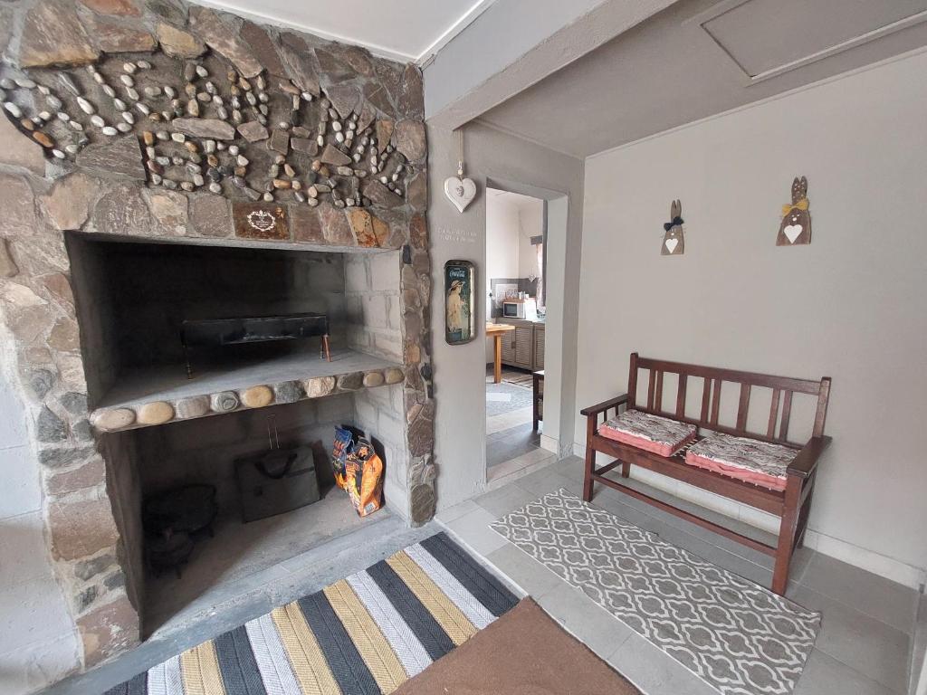 - un salon avec une cheminée en pierre et un banc dans l'établissement Klein Desert Song, à Kleinsee