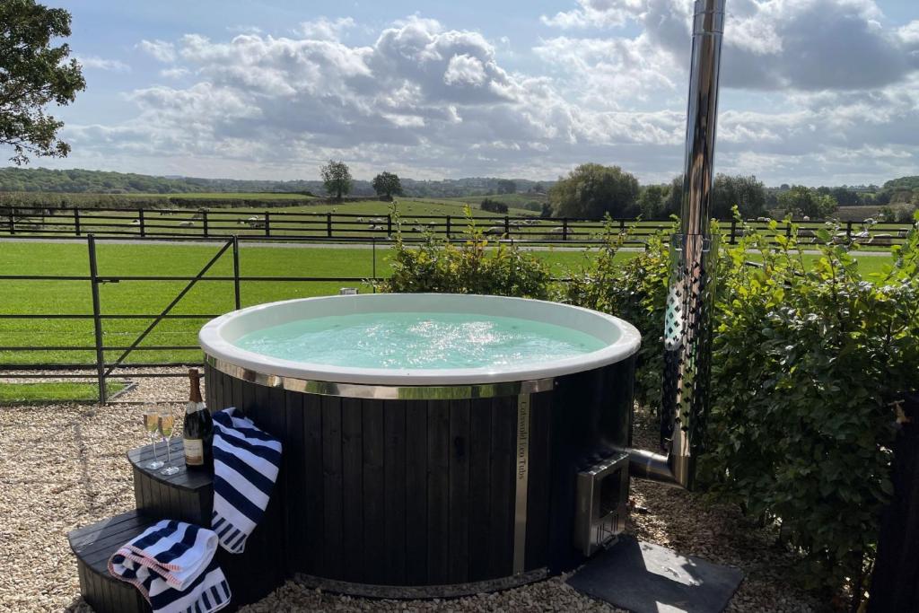 una bañera de hidromasaje en un jardín con vistas a un campo en The Blended Barn, en Stratford-upon-Avon