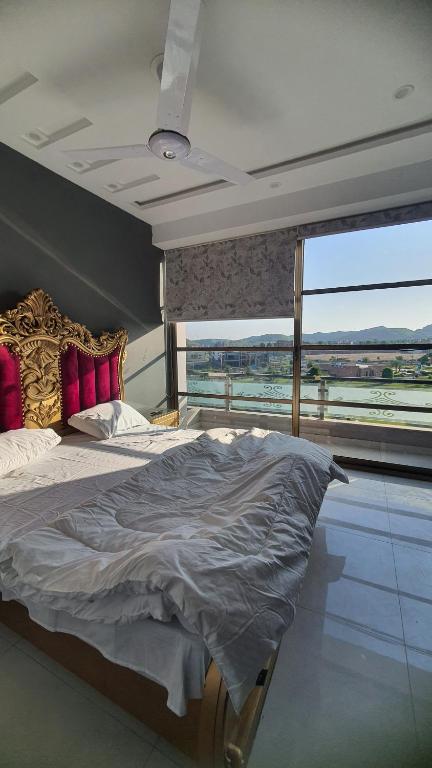 ein Schlafzimmer mit einem großen Bett und einem großen Fenster in der Unterkunft Citi Hotel Apartments in Jhelum