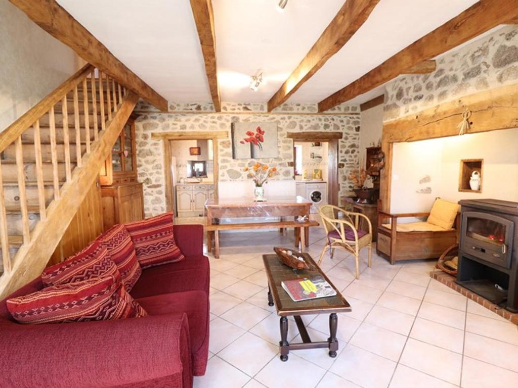 a living room with a red couch and a fireplace at Gîte Sansac-Veinazès, 3 pièces, 4 personnes - FR-1-742-114 