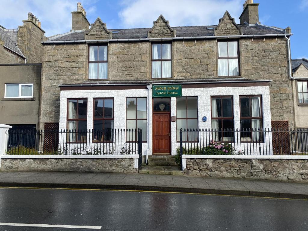 ein Backsteingebäude mit einer roten Tür auf einer Straße in der Unterkunft Alder Lodge Guest House in Lerwick