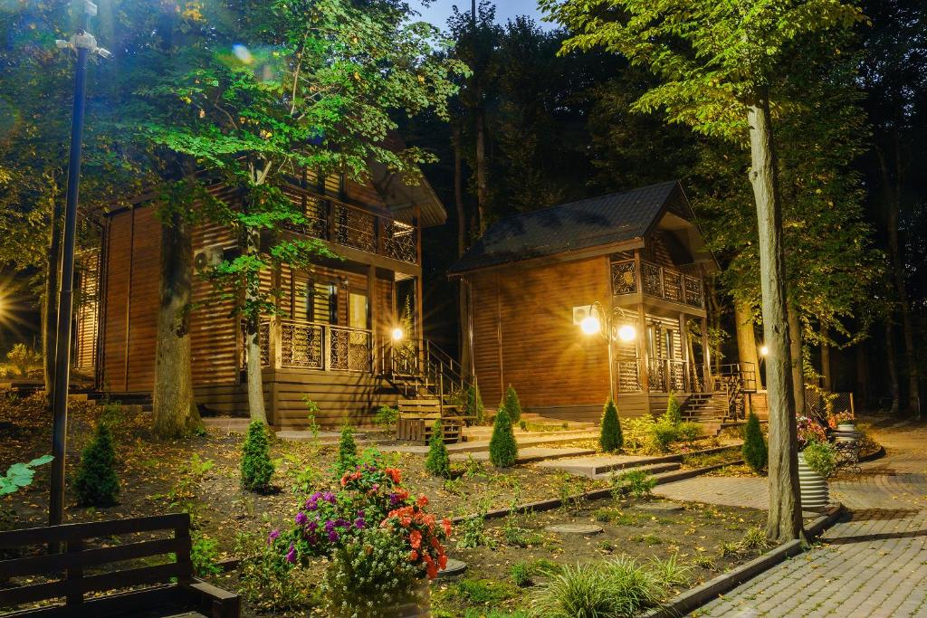 une cabane en bois éclairée dans un jardin la nuit dans l'établissement Готельно-ресторанний комплекс БОЖЕДАР, à Vinnytsia