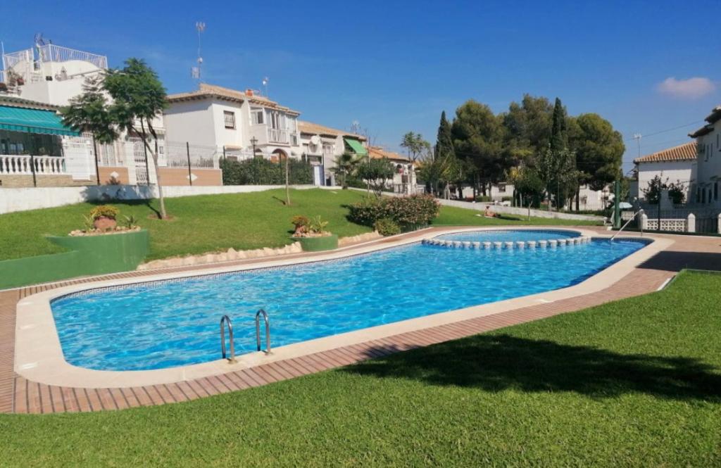 ein großer Pool in der Mitte eines Gartens in der Unterkunft Apartament Casa del Gato Rojo , communal swimming pool , terrace with barbecue in Torrevieja
