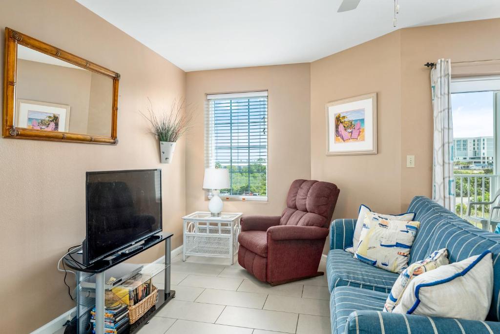 ein Wohnzimmer mit einem blauen Sofa und einem TV in der Unterkunft Grande Caribbean 326 in Orange Beach