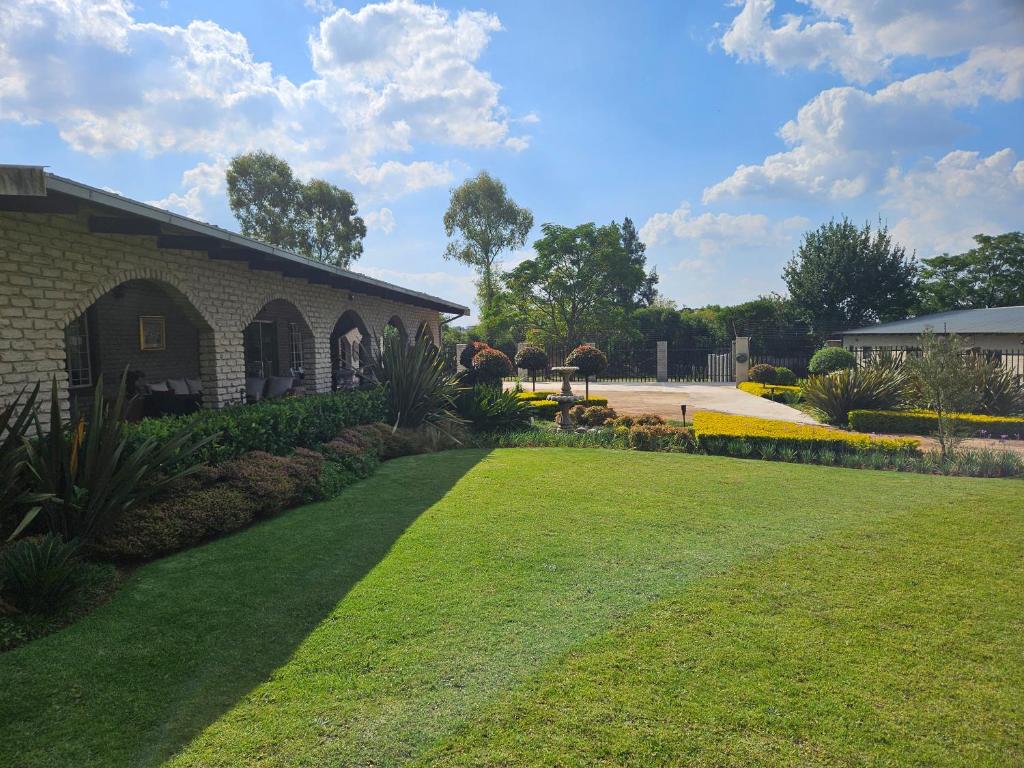 a yard with a brick building and a grass field at Zacks Country Stay in Krugersdorp