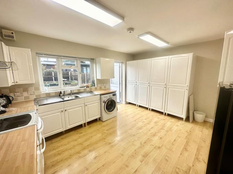 a kitchen with white cabinets and a wooden floor at 5 Bedroom house in DA7 in Erith