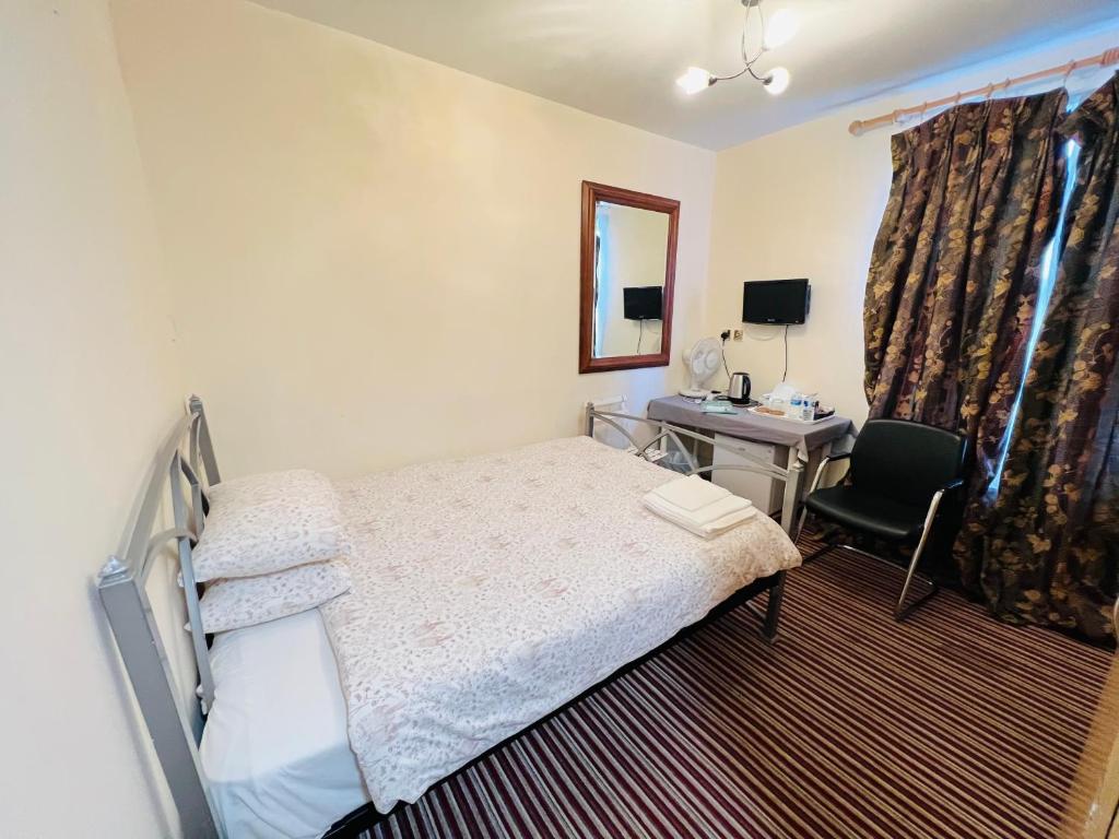 1 dormitorio con cama, escritorio y silla en Aron Guest House, en Ealing