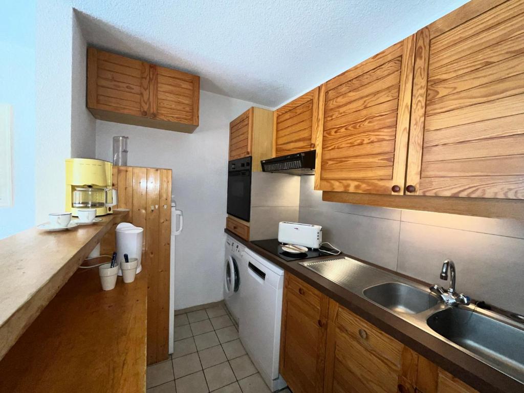 a small kitchen with wooden cabinets and a sink at Appartement Méribel, 3 pièces, 6 personnes - FR-1-688-36 in Méribel