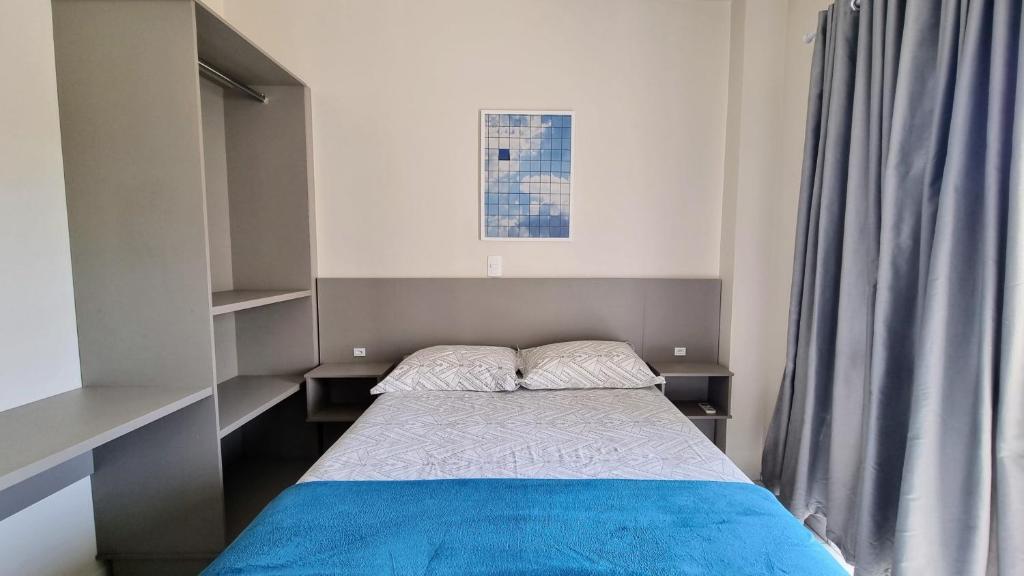 Dormitorio pequeño con cama con manta azul en Ed. Camboim, en Bombinhas