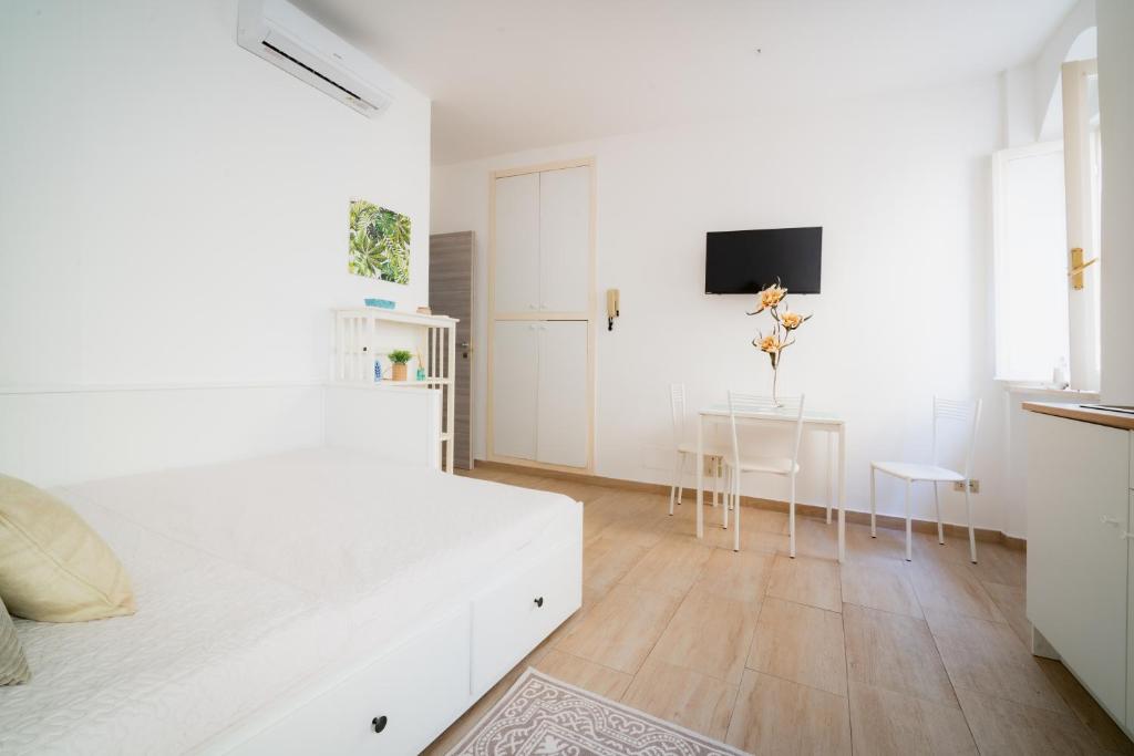 a white bedroom with a white bed and a table at APT per coppie nel cuore di Desenzano CASTELLO in Desenzano del Garda