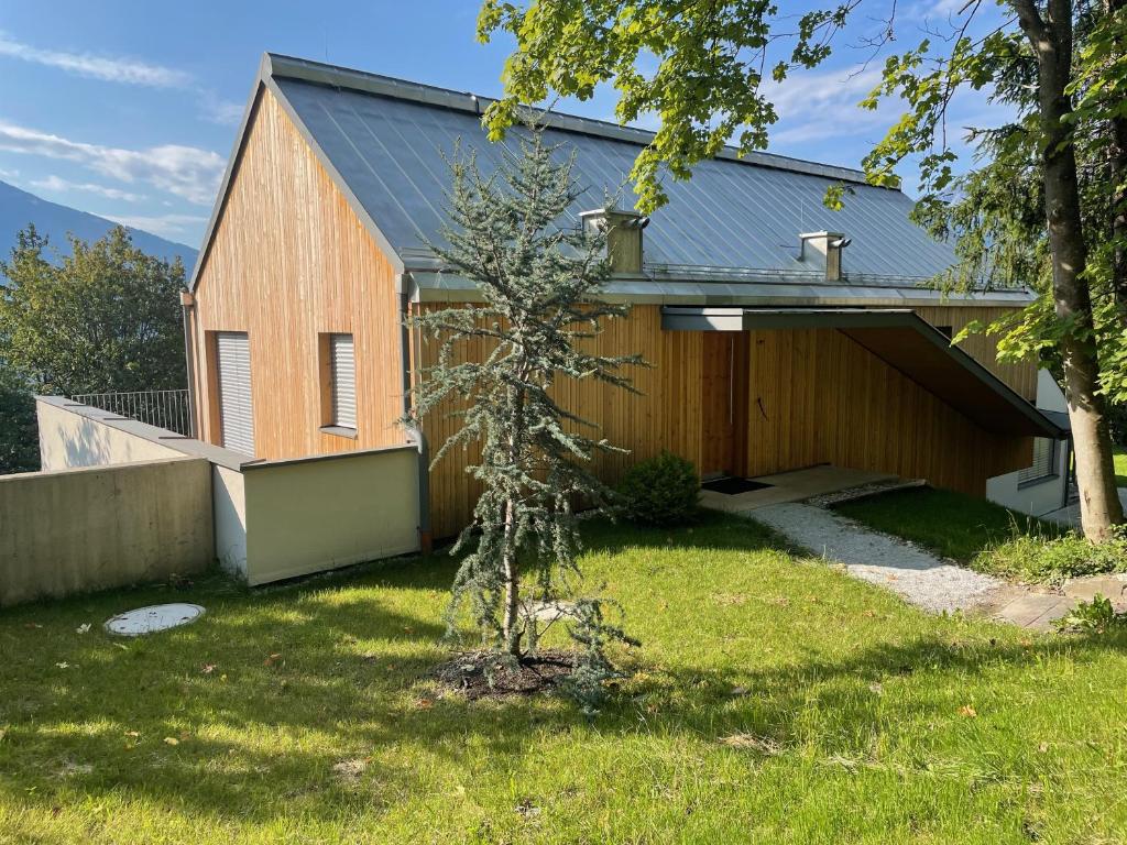 une maison en bois avec un arbre dans la cour dans l'établissement Blickfang Tirol, à Innsbruck